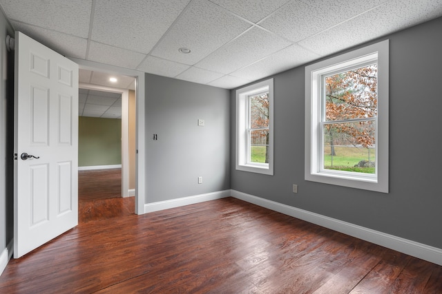 spare room with dark hardwood / wood-style flooring and a paneled ceiling