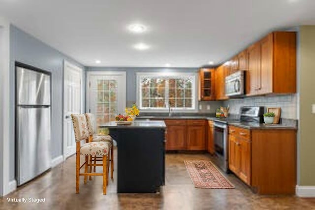 610 W Neck Rd, Nobleboro, ME 04555 - kitchen with appliances with stainless steel finishes, a kitchen island, a breakfast bar, brown cabinets, and dark countertops