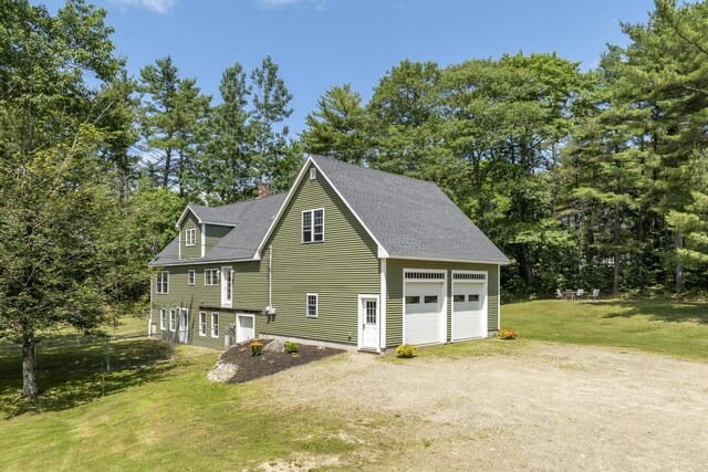 610 W Neck Rd, Nobleboro, ME 04555 - view of side of home featuring a lawn, a chimney, view of scattered trees, a shingled roof, and a garage
