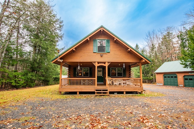 cabin with covered porch, an outbuilding, and a garage