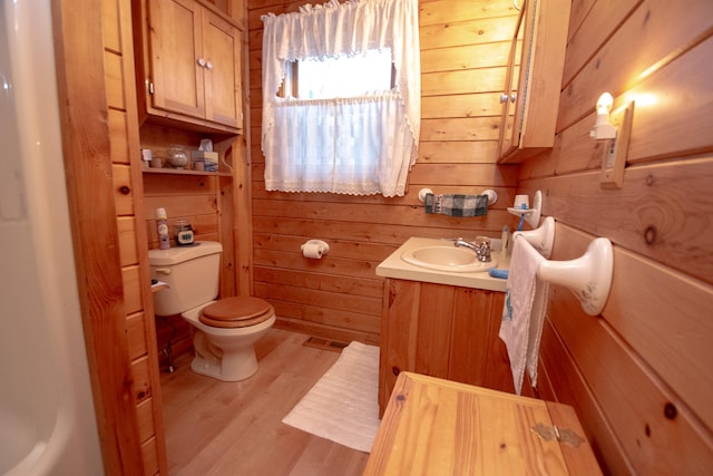 bathroom with hardwood / wood-style flooring, toilet, wood walls, and vanity