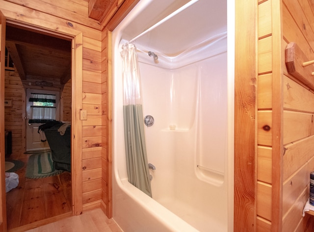 bathroom featuring wood walls, shower / tub combo with curtain, and wood-type flooring