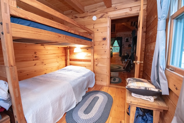 bedroom featuring wood ceiling, beam ceiling, wooden walls, and hardwood / wood-style flooring