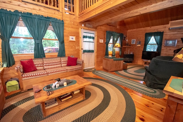 living room featuring a wall unit AC, beam ceiling, wooden walls, wood-type flooring, and wooden ceiling