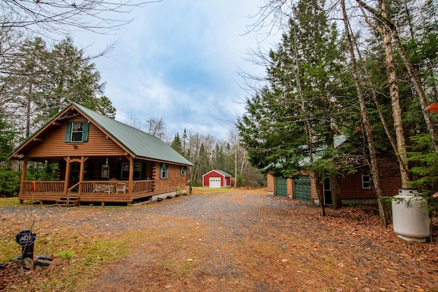 865 Barnard Rd, Williamsburg Twp, ME 04414 - view of side of property with an outdoor structure, log exterior, metal roof, a porch, and driveway