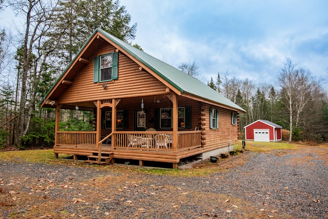 log home with a garage, a porch, and an outdoor structure