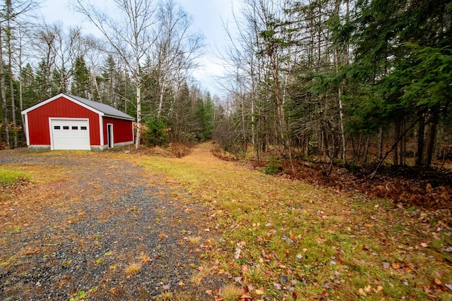 865 Barnard Rd, Williamsburg Twp, ME 04414 - view of yard with driveway, an outdoor structure, a detached garage, and a forest view