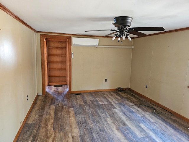 empty room featuring built in features, ceiling fan, a wall unit AC, dark wood-type flooring, and crown molding