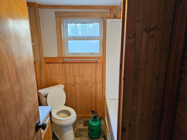 full bathroom with bathtub / shower combination, vanity, wooden walls, and toilet