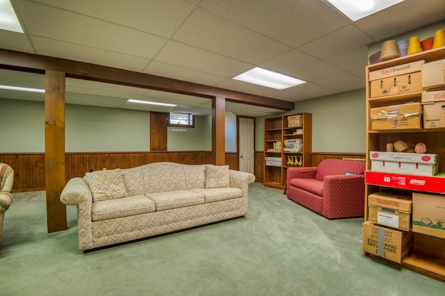 living room featuring a paneled ceiling, wooden walls, and carpet floors