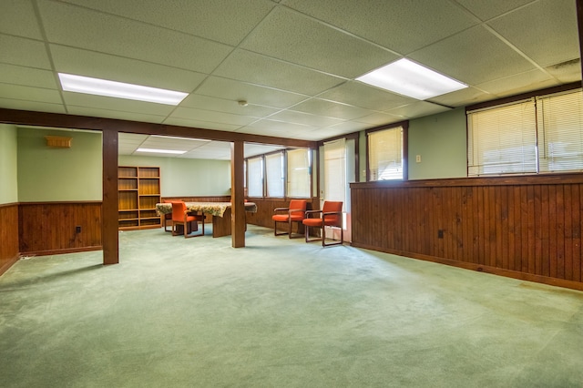 basement with wood walls, a paneled ceiling, and carpet flooring