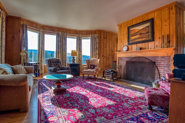 living room featuring a brick fireplace, hardwood / wood-style flooring, wood walls, and plenty of natural light