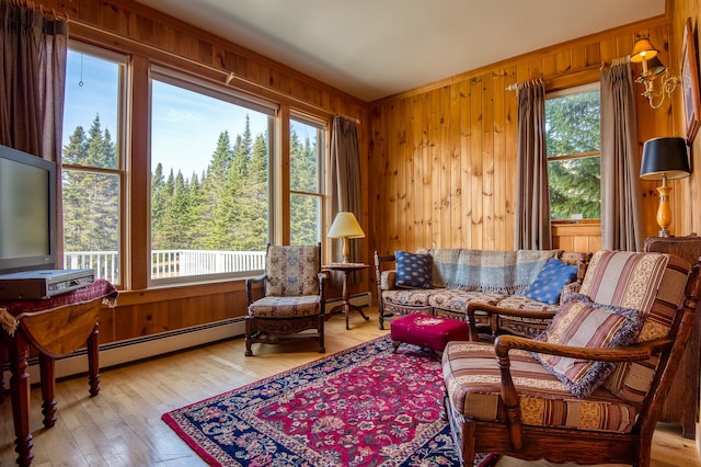 living area with a baseboard heating unit, light hardwood / wood-style floors, and wood walls