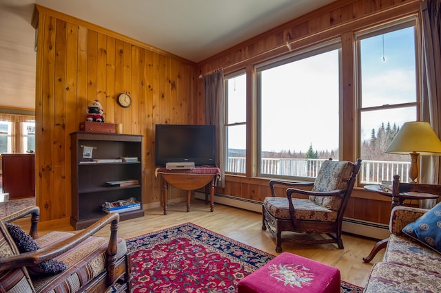 interior space featuring light wood-type flooring, wooden walls, ornamental molding, and a baseboard heating unit