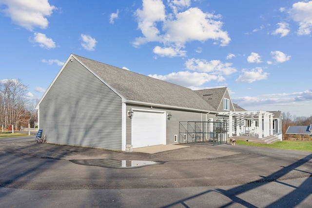 view of property exterior with a garage and a pergola