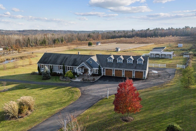 view of front of home featuring a front yard, covered porch, a garage, and a rural view