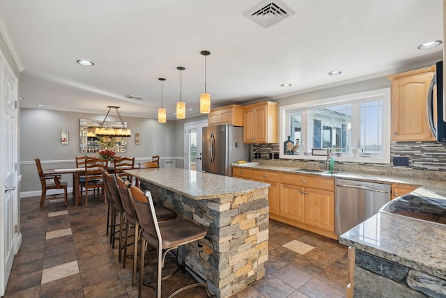 kitchen featuring appliances with stainless steel finishes, sink, backsplash, a center island, and hanging light fixtures