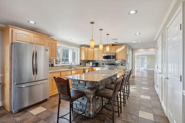 kitchen with hanging light fixtures, ornamental molding, a center island, appliances with stainless steel finishes, and light stone counters