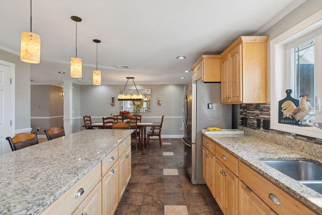 kitchen featuring crown molding, stainless steel fridge, pendant lighting, light stone counters, and light brown cabinets