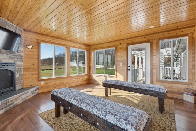 sunroom with a stone fireplace and wood ceiling