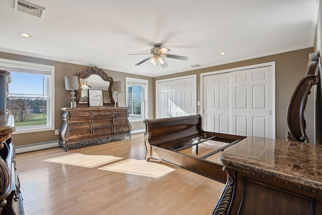 bedroom with light hardwood / wood-style floors, crown molding, baseboard heating, and ceiling fan