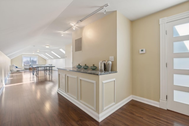 interior space featuring dark wood-type flooring, rail lighting, and vaulted ceiling