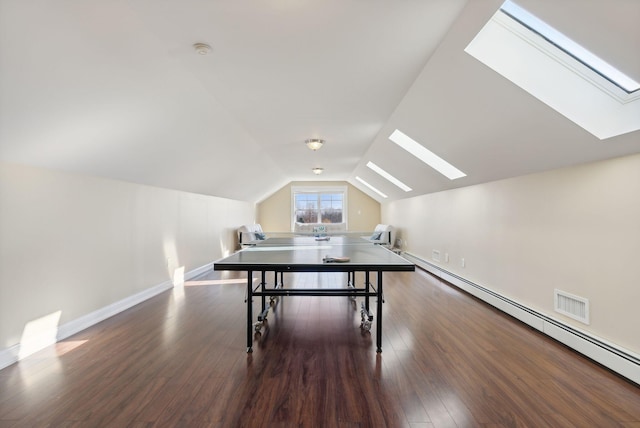 interior space featuring vaulted ceiling with skylight, a baseboard heating unit, and dark wood-type flooring