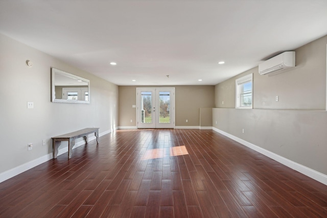 empty room with a wall unit AC, french doors, and dark wood-type flooring