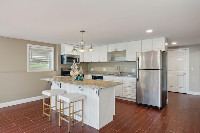 kitchen with white cabinetry, appliances with stainless steel finishes, decorative light fixtures, and dark hardwood / wood-style flooring