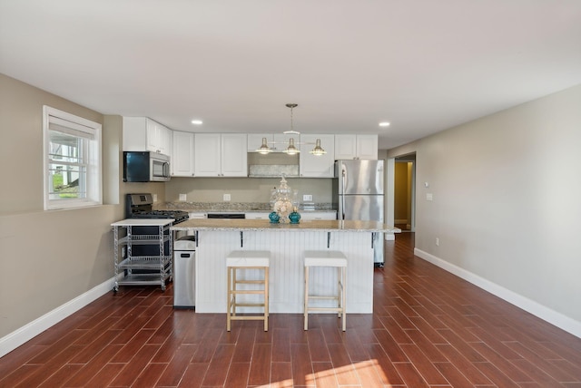 kitchen with appliances with stainless steel finishes, decorative light fixtures, dark hardwood / wood-style floors, and white cabinets