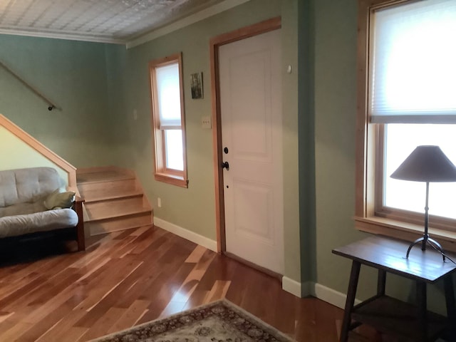 foyer entrance with crown molding, a wealth of natural light, and dark hardwood / wood-style floors