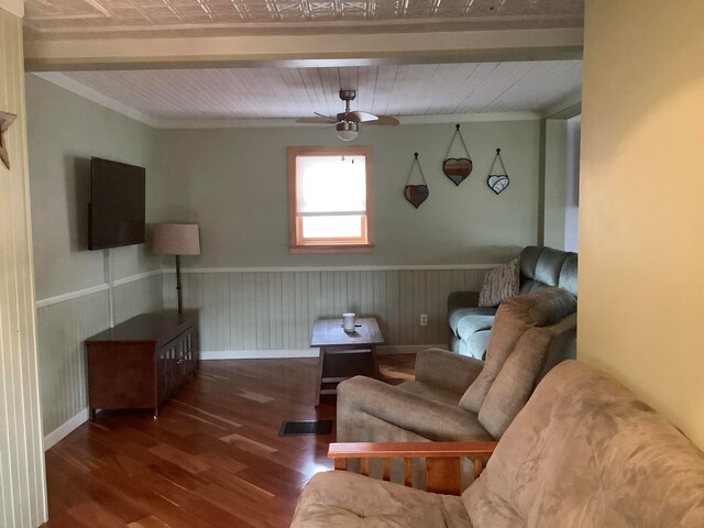 living room featuring crown molding, beamed ceiling, dark wood-type flooring, and ceiling fan