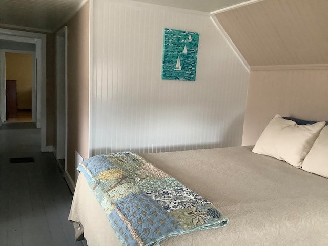 bedroom with wood walls, hardwood / wood-style flooring, and vaulted ceiling