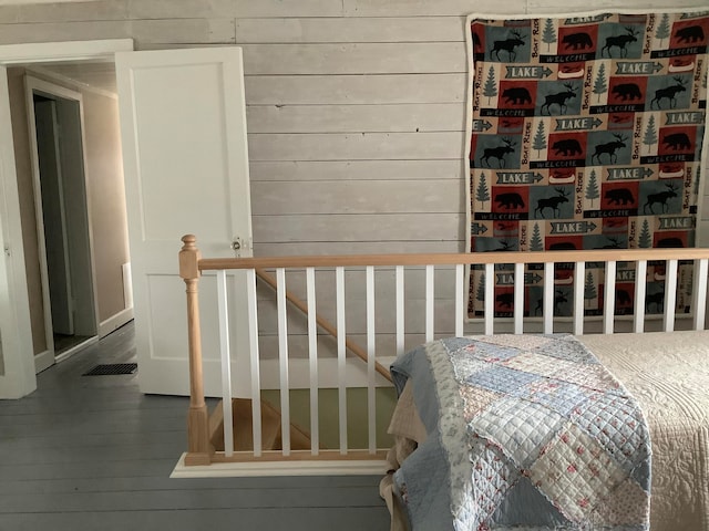 bedroom with hardwood / wood-style floors and wooden walls