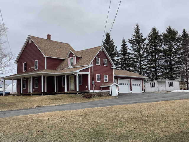 view of front of house with a porch, a front yard, a shed, and a garage