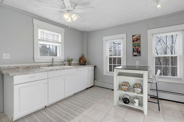 kitchen with white dishwasher, light tile patterned flooring, baseboard heating, and sink