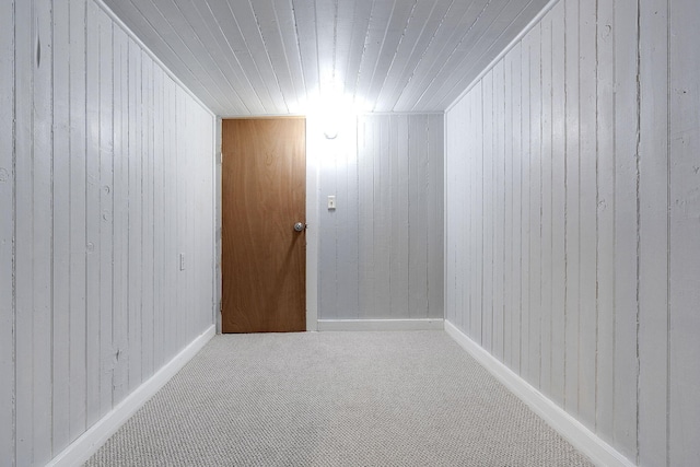 carpeted spare room with wood walls