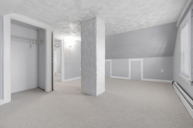 unfurnished bedroom with a baseboard heating unit, light colored carpet, and vaulted ceiling