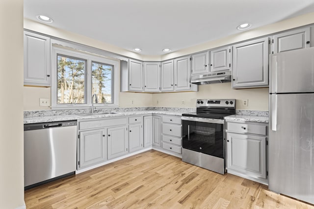 kitchen featuring light stone counters, gray cabinetry, stainless steel appliances, sink, and light hardwood / wood-style floors