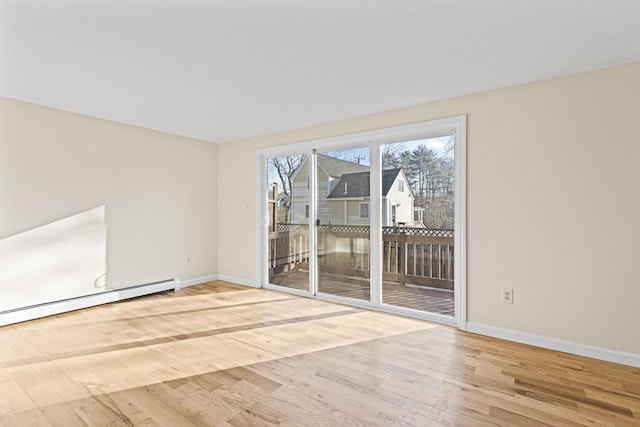 spare room featuring baseboard heating and light hardwood / wood-style flooring