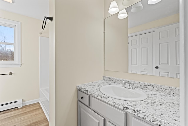 bathroom featuring vanity, wood-type flooring, bathing tub / shower combination, and a baseboard radiator