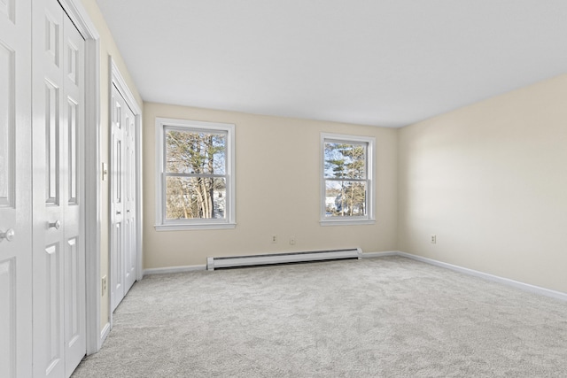 unfurnished bedroom featuring a baseboard heating unit, light carpet, and multiple closets