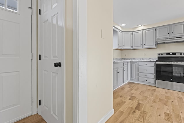 kitchen featuring light stone countertops, light hardwood / wood-style floors, stainless steel electric range oven, and gray cabinetry