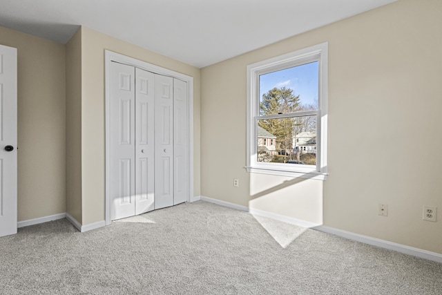 unfurnished bedroom with light colored carpet and a closet