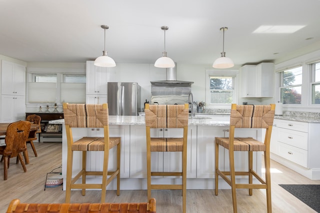 kitchen with light hardwood / wood-style floors, stainless steel refrigerator, and pendant lighting