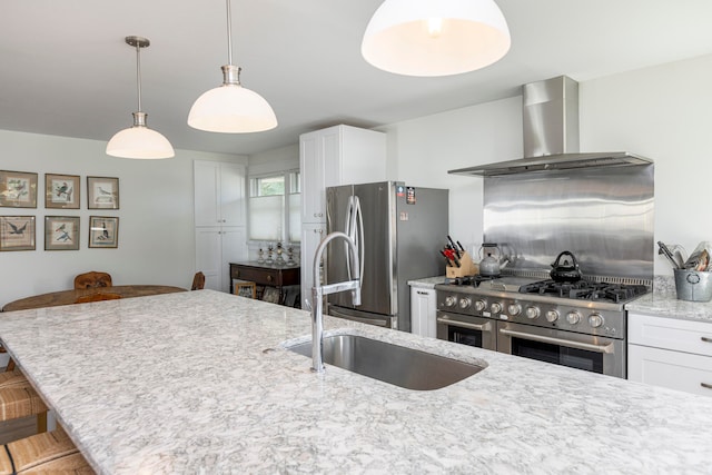 kitchen featuring wall chimney exhaust hood, white cabinetry, a breakfast bar, and appliances with stainless steel finishes