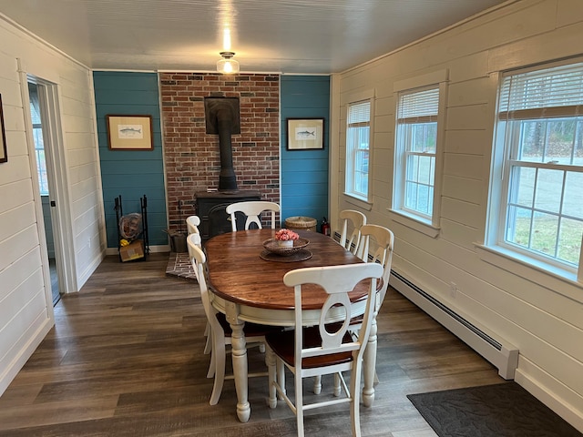 dining area featuring a wood stove, wood walls, dark hardwood / wood-style floors, and a baseboard heating unit