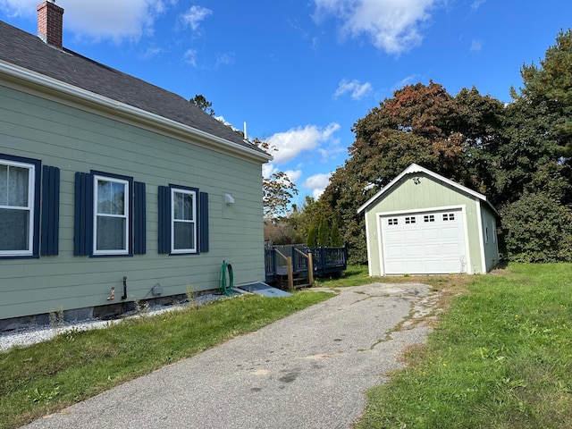 view of side of home featuring a garage, a lawn, and an outdoor structure