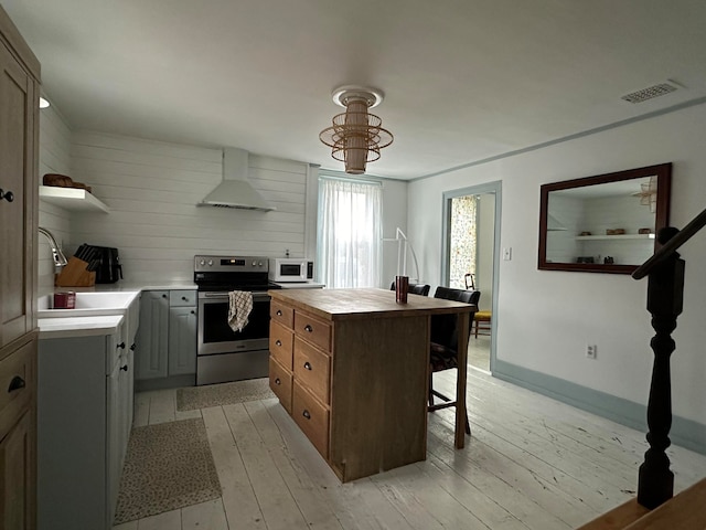 kitchen featuring a center island, sink, stainless steel electric stove, light hardwood / wood-style flooring, and range hood