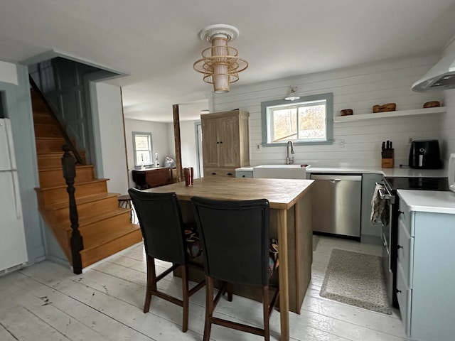 kitchen featuring a kitchen island, range with electric cooktop, sink, light hardwood / wood-style floors, and dishwasher